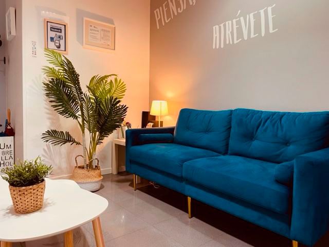 Imagen de sala de espera con muebles claros, sofá azul y pared gris con texto escrito en letras blancas
